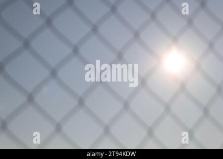Photo of the sun through a mesh fence. Focus on the Sun Stock Photo