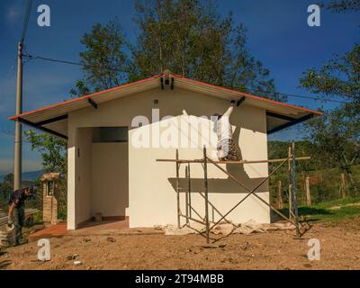 A woman worker standing on a scaffolding and a man in the side give the final touches to a workshop, in a farm in the eastern Andean mountains of cent Stock Photo
