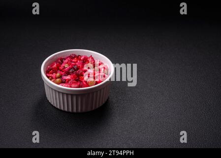 Delicious juicy vinigret salad of boiled vegetables potatoes, beets, pot, cabbage and carrots with salt and spices on a dark concrete background Stock Photo