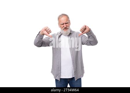 well-groomed gray-haired senior man with a beard and mustache in a shirt shows a dislike Stock Photo