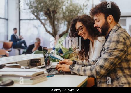 Lovely couple collaborate on projects and share ideas, discussing growth and innovation in a modern office. Stock Photo
