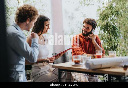 An diverse group of architects, engineers, and contractors discuss blueprints and project details at a vibrant coffee bar. Stock Photo