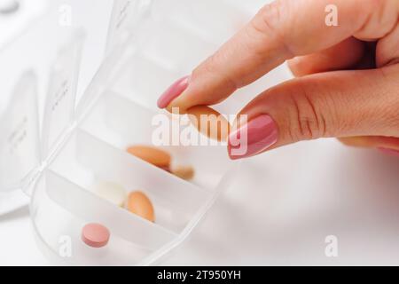 Woman hand taking pill from pillbox or organizer for daily medication Stock Photo