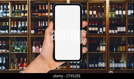 Online service for alcohol delivery. Liquor delivery mobile app mockup. Smart phone with blank screen in front of wine bottles on shelves in store. Stock Photo