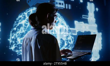 Certified admin writing artificial intelligence script code in startup workspace on laptop terminal. Knowledgeable expert doing maintenance work in high tech facility updating AI systems Stock Photo