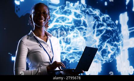 Portrait of cheerful IT executive updating AI systems, writing intricate binary code scripts on laptop. System administrator using programming to upgrade artificial intelligence simulation model Stock Photo