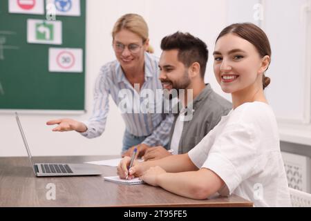 Happy woman making notes at desk in class during lesson in driving school Stock Photo