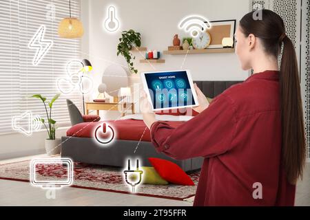 Woman using smart home control system via application on tablet indoors. Different icons connected with device Stock Photo