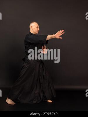 Portrait of aikido sensei master with black sensei belt in taekwondo kimono on black background. Traditional samurai hakama kimono. Healthy lifestyle Stock Photo