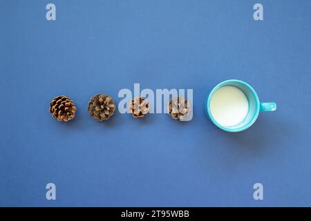 Cup of milk with pine cone on navy blue background. top view Stock Photo