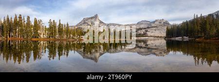 Sierra Nevada Granite Mountain Peak Reflected in Calm Water of Treelined Lower Cathedral Lake.  Scenic Yosemite National Park Panoramic Landscape Stock Photo