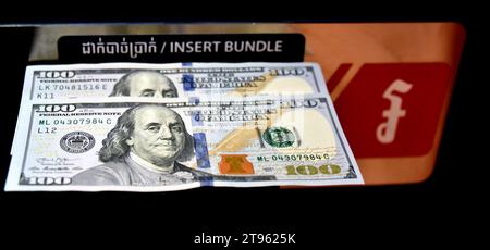 Two one hundred dollar or $100 notes cash banknotes on a banking machine that reads 'insert bundle' with khmer and english text in Phnom Penh  Cambodia Stock Photo