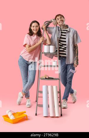 Young couple with painting tools on pink background Stock Photo