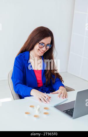 Woman in blue clothes working on laptop in business office Stock Photo