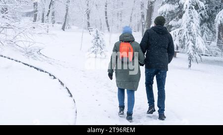Loving couple walking in winter park in the snowfall. Stock Photo