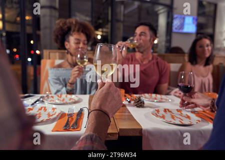 Cold glass of white wine at restaurant among young friends having fun together while spending time Stock Photo