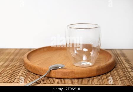 Empty double wall cup for tea or coffee on a table in a restaurant, cafe. Transparent cylindrical crystal mug over wooden table in the bar. Space for Stock Photo