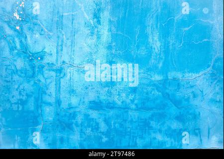 Wall with bright light blue paint on surface, damaged cracked surface as texture or background Stock Photo