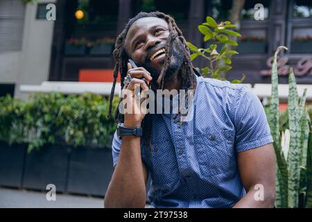 Young black man with dreadlocks laughing while holding his head ...
