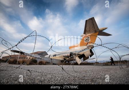 Abandoned destroyed airplane and metal border fence Stock Photo