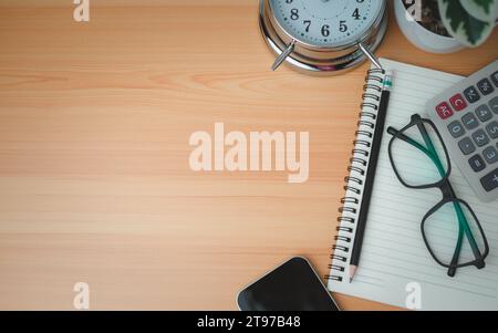Office table of modern workplace with notebooks and pencils, phone, clock on wooden table. side view and copy space on wooden floor, Flat lay, side vi Stock Photo