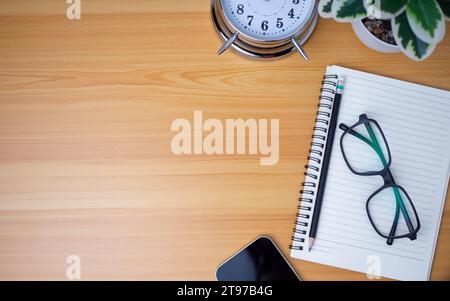 Office table of modern workplace with notebooks and pencils, phone, clock on wooden table. Top view and copy space on wooden floor, Flat lay, top view Stock Photo