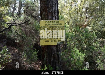 A sign at the trailhead of a forest hiking trail on the Greek island of Ikaria, a "blue zone" in the Aegean Sea, near Profitis Ilias, Greece. Stock Photo