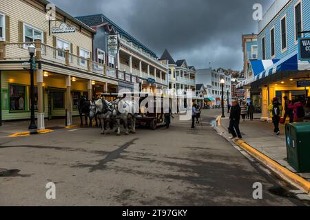 Main street on Mackinac Island with horse-drawn carriages and stores. Street scene on Mackinac Island, where motor vehicles are prohibited. Mackinac Island, United States Stock Photo