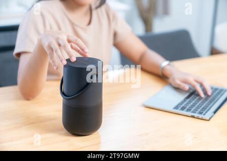 working woman using portable speaker to online meeting or listening to music at home Stock Photo