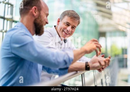 Colleagues discussing innovative business solutions leaning standing in office corridor Stock Photo