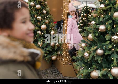 Boy with girl standing near Christmas trees at market Stock Photo