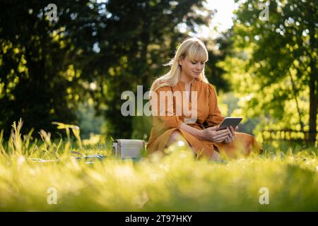Woman using tablet PC in park on sunny day Stock Photo