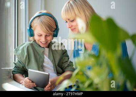 Smiling mother with son using tablet PC at home Stock Photo