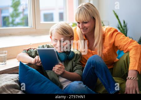 Happy woman with son using tablet PC at home Stock Photo