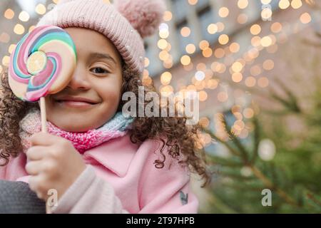 Girl wearing pink knit hat holding lollipop candy Stock Photo