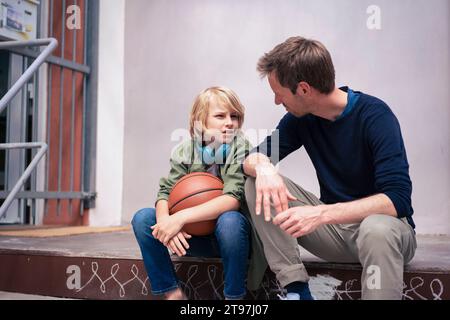 Father talking with son sitting on steps Stock Photo