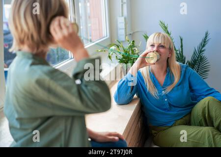 Mother talking with son through tin can phone Stock Photo