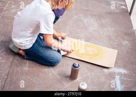 Boy spraying with aerosol can on cardboard Stock Photo
