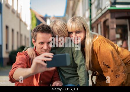 Happy father taking selfie with woman and son through smart phone Stock Photo