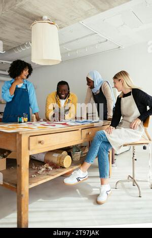 Happy artists discussing with paintings on desk in studio Stock Photo