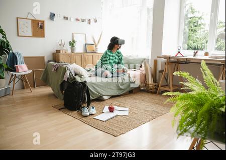 Teenage girl wearing virtual reality simulators playing video game with controller at home Stock Photo