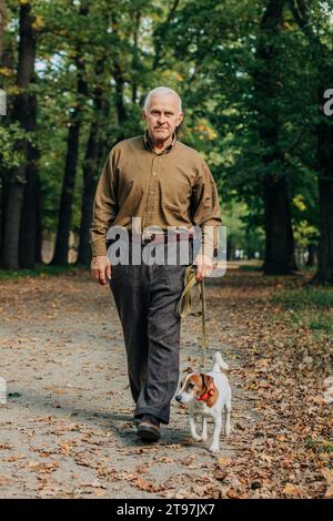 Senior man walking with Jack Russell Terrier dog in park Stock Photo