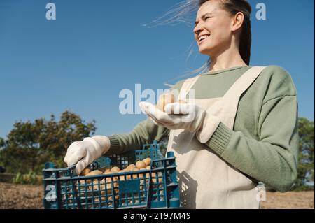 Smiling farmer holding potato crate at farm Stock Photo