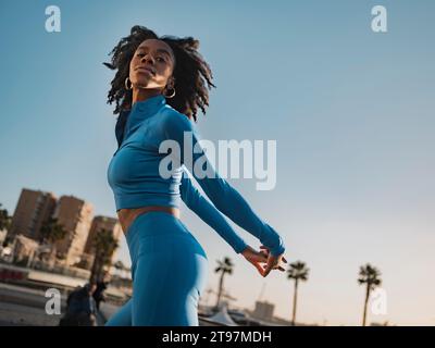 Beautiful woman in sports clothing posing with hands behind back Stock Photo