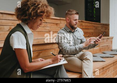 Businessman using tablet PC with smiling colleague writing on document Stock Photo