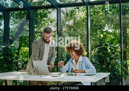 Happy designers having discussion over laptop at desk in office Stock Photo
