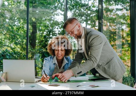 Happy designers having discussion over documents and pyramid models in office Stock Photo