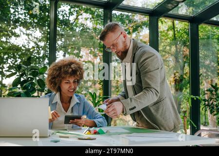 Smiling designers having discussion over documents and pyramid models in office Stock Photo
