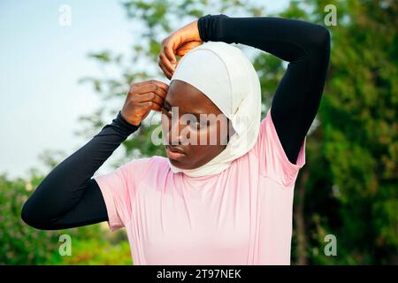 Young woman adjusting hijab at park Stock Photo