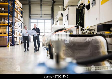 Engineers holding document and having discussion in factory Stock Photo